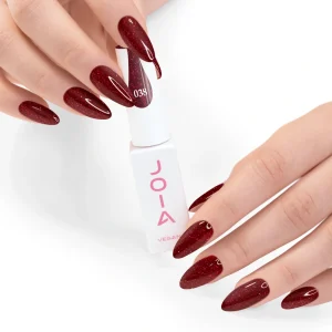 JOIA Vegan Gel Polish 038 Ruby Red Shimmer 6ml — hand holding bottle with painted nails